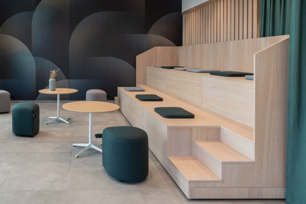 Tribüne in der Cafeteria des DonauTower – warmes Holz und grüne Akustikvorhänge